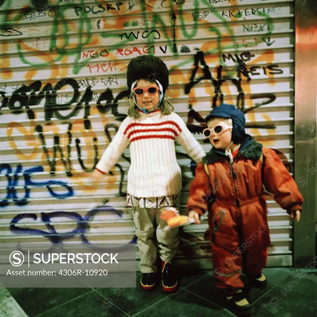 Two Scandinavian girls in front of a wall with graffiti on it, Stockholm, Sweden.