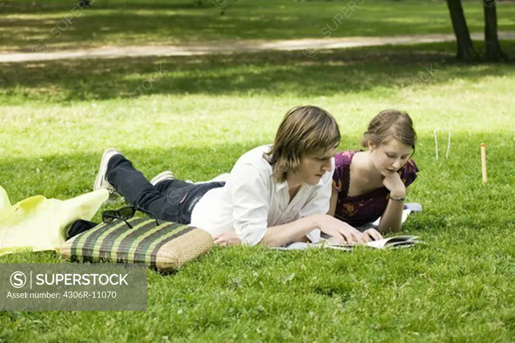 Young scandinavian couple reading a book together outdoors, Sweden.
