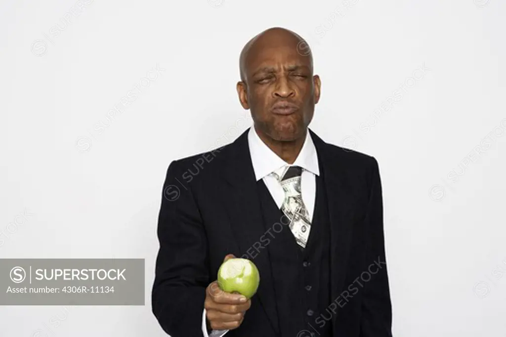 A middle aged man wearing a suit eating an apple.
