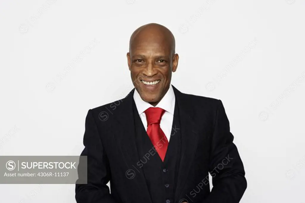 A middle aged man wearing a suit en a red tie.