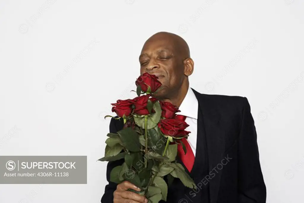 A man in a suit holding a bunch of red roses.