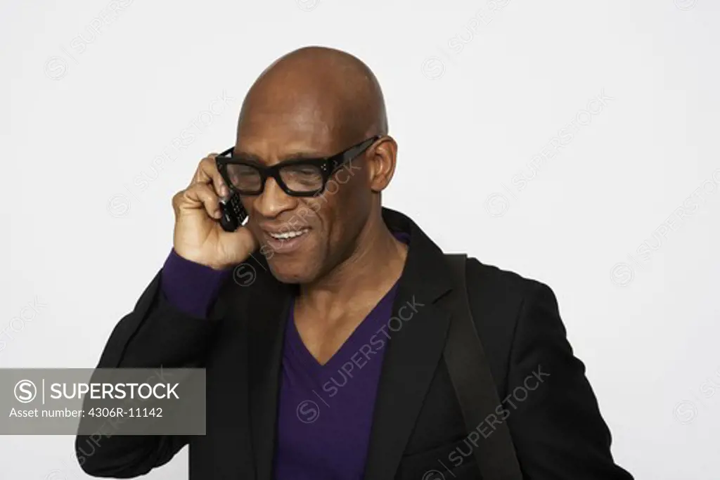 A man with glasses talking in a cellphone.