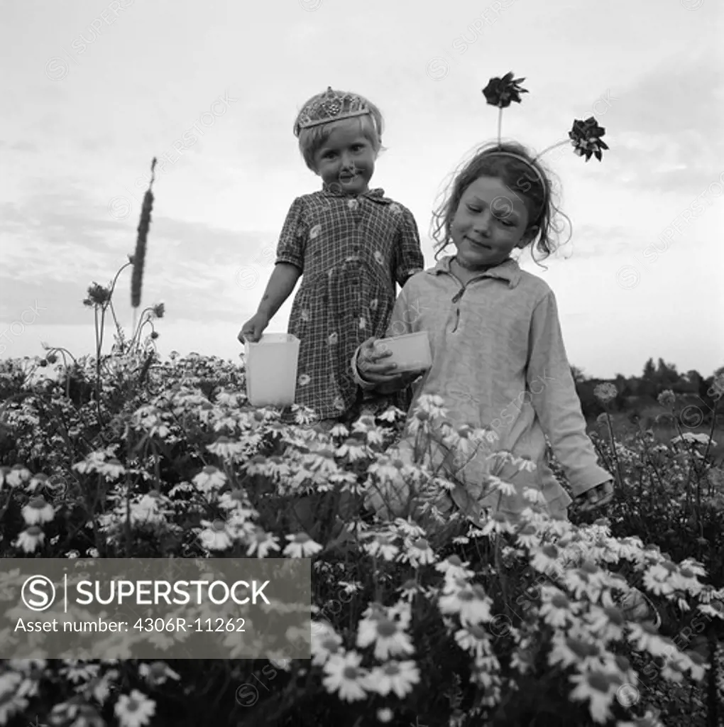 Two girls standing in a meadow full of flowers, Oland, Sweden.