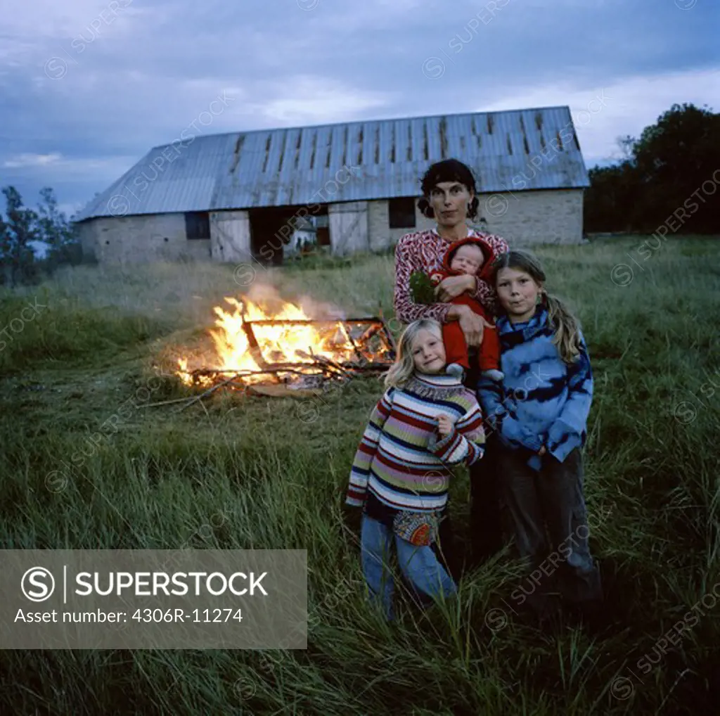Mother and her daughters standing in front of a fire, Oland, Sweden.