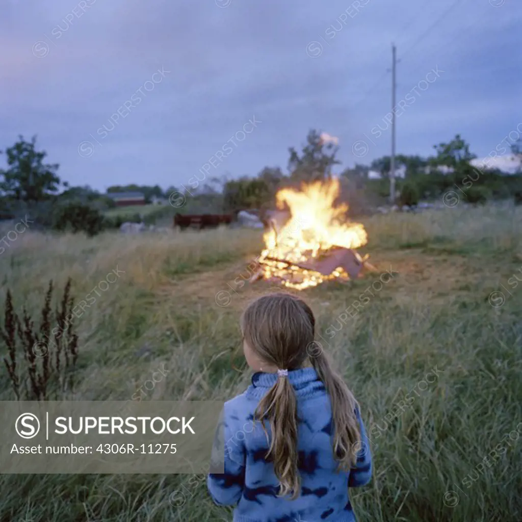 A girl by a fire a summer night, Sweden.