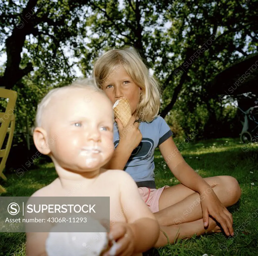 Two children eating ice cream in a garden, Sweden.