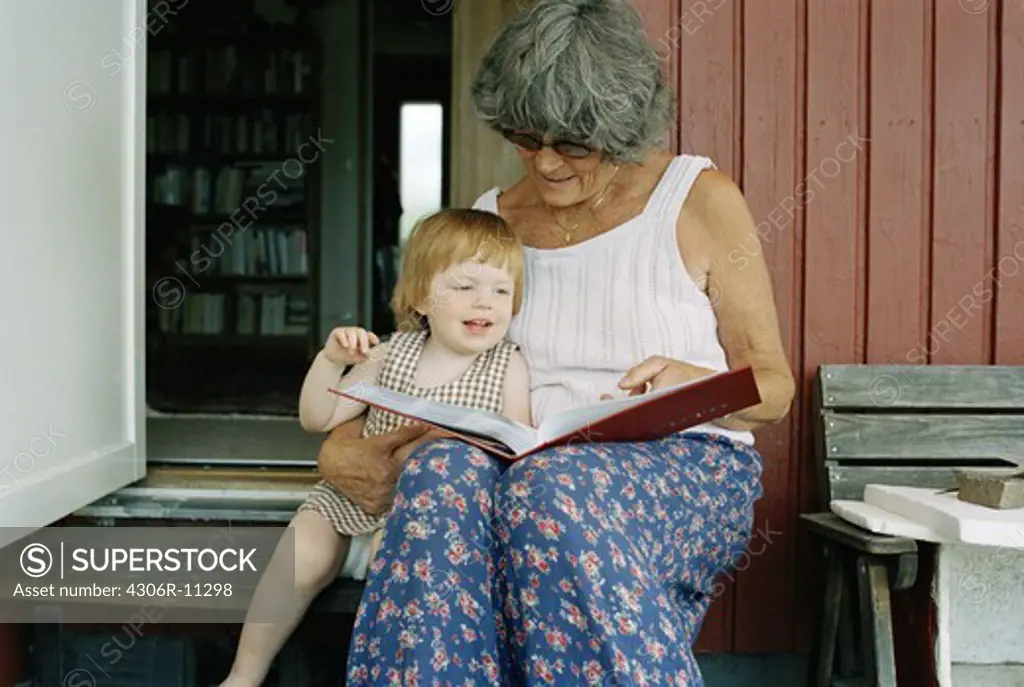 Grandmother and granddaughter reading a book, Sweden.