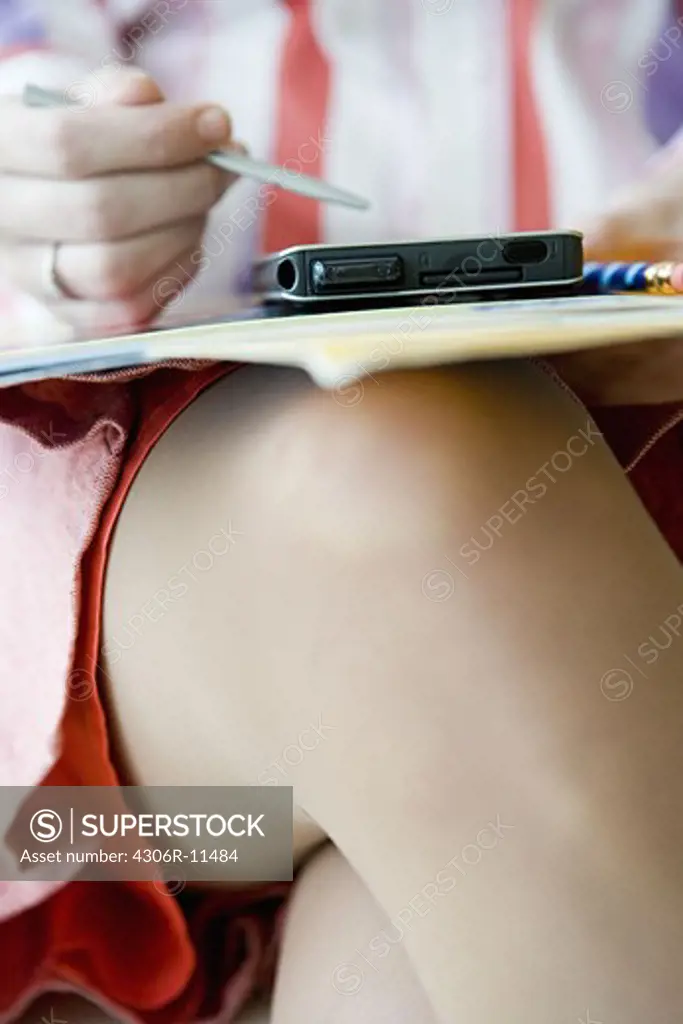 Woman sitting with a personal digital assistant and papers in  her lap, Stockholm, Sweden.