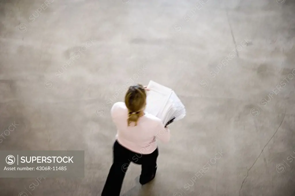 A woman carrying a pile of paper in an office, seen from above, Sweden.