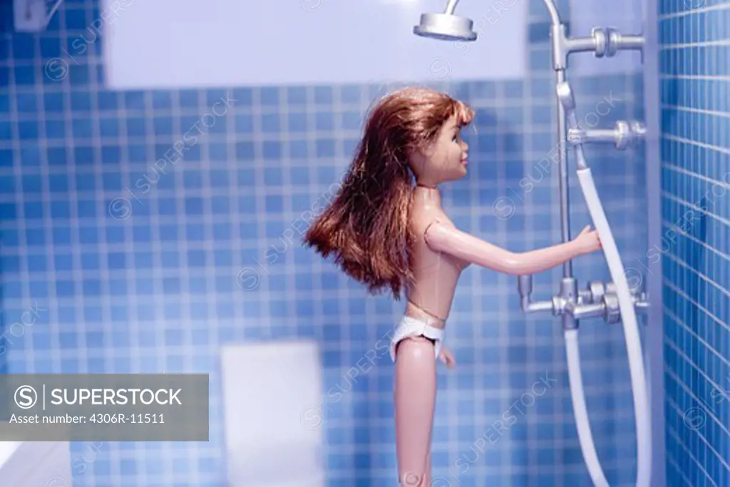 A doll having a shower in a doll house.