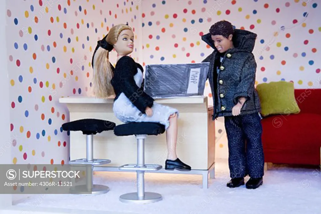 Two barbie dolls in a dolls house.