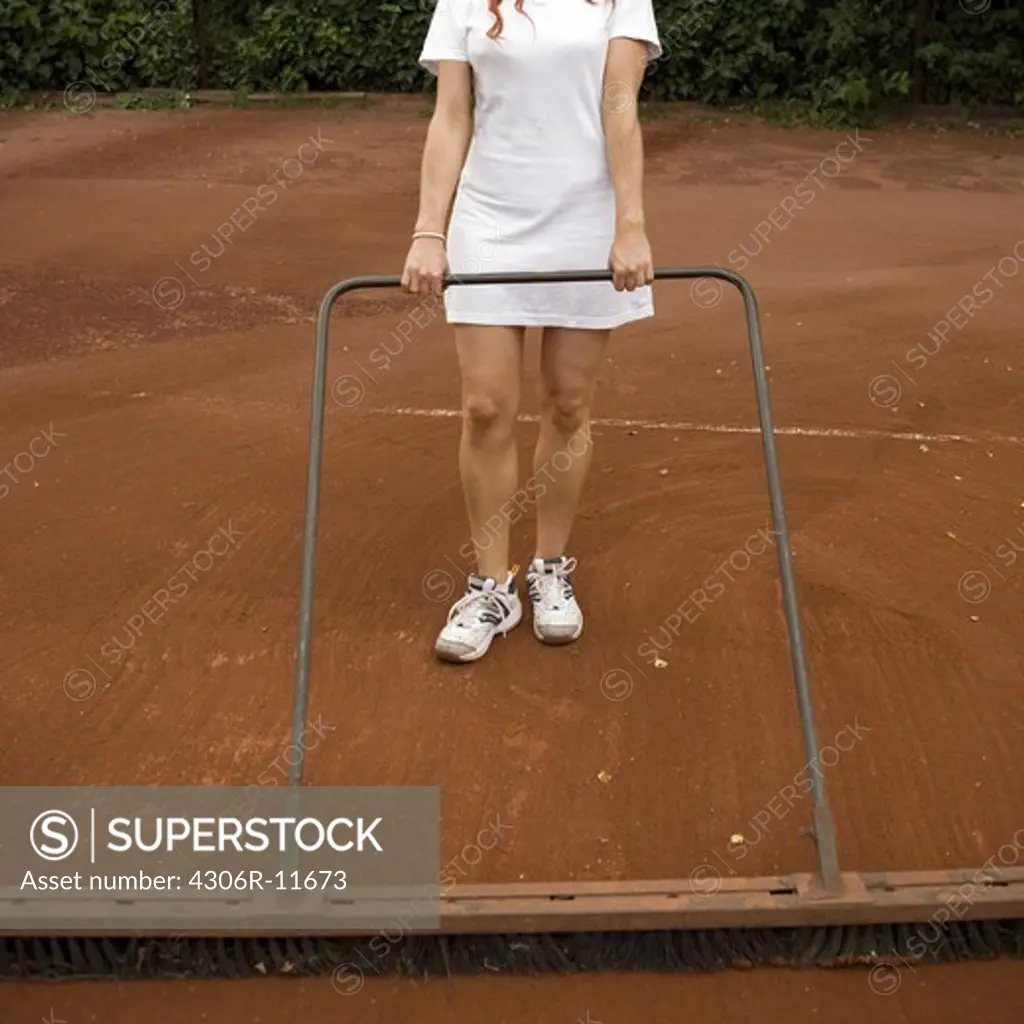 A woman preparing a tennis court.