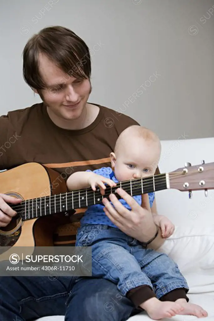 A man and a baby playing guitarr.
