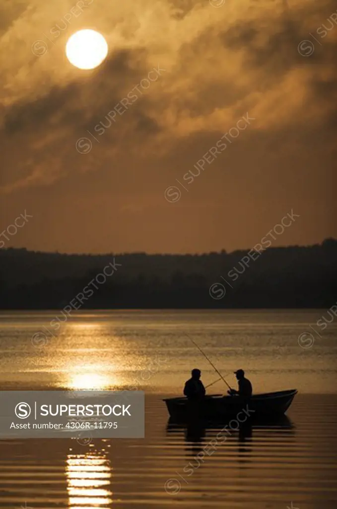 Two persons sitting in a boat fishing at night, Mariefred, Sweden.