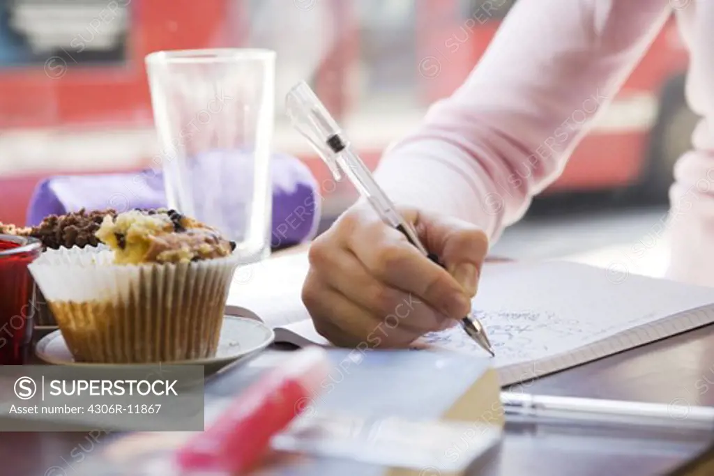 A woman writing in her note book in a cafe.