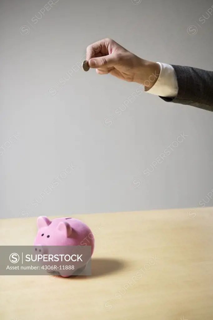 A man inserting money into a piggy bank.