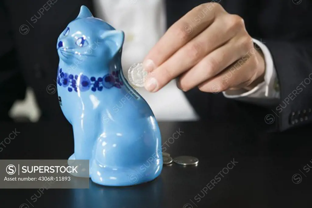 A man inserting money into a piggy bank.