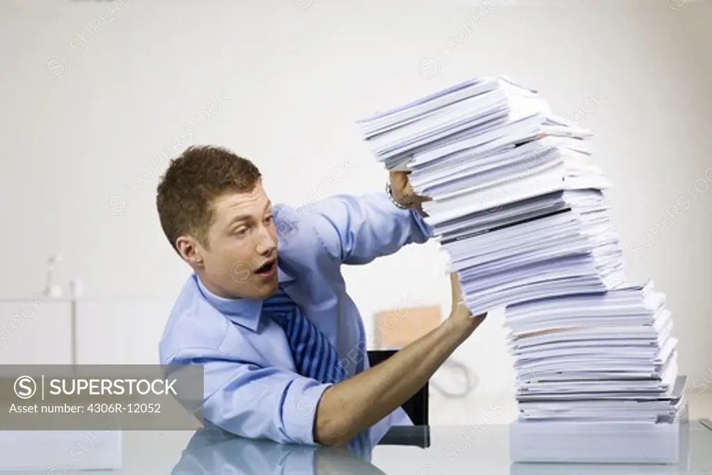 A man with a pile of paper in an office.