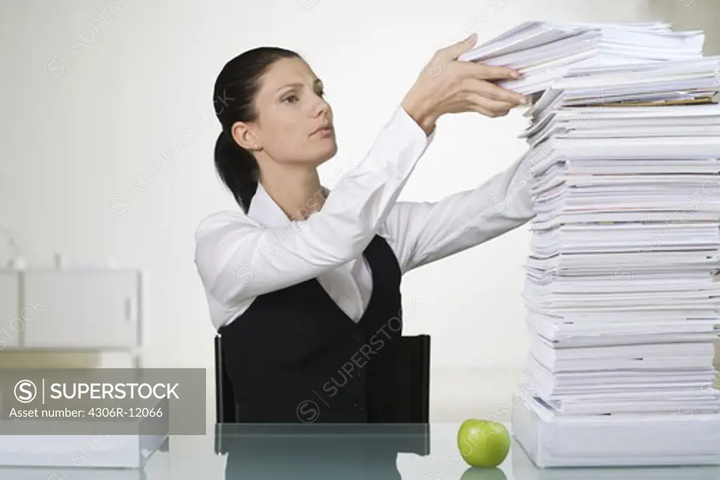 A woman in an office next to a pile of paper.