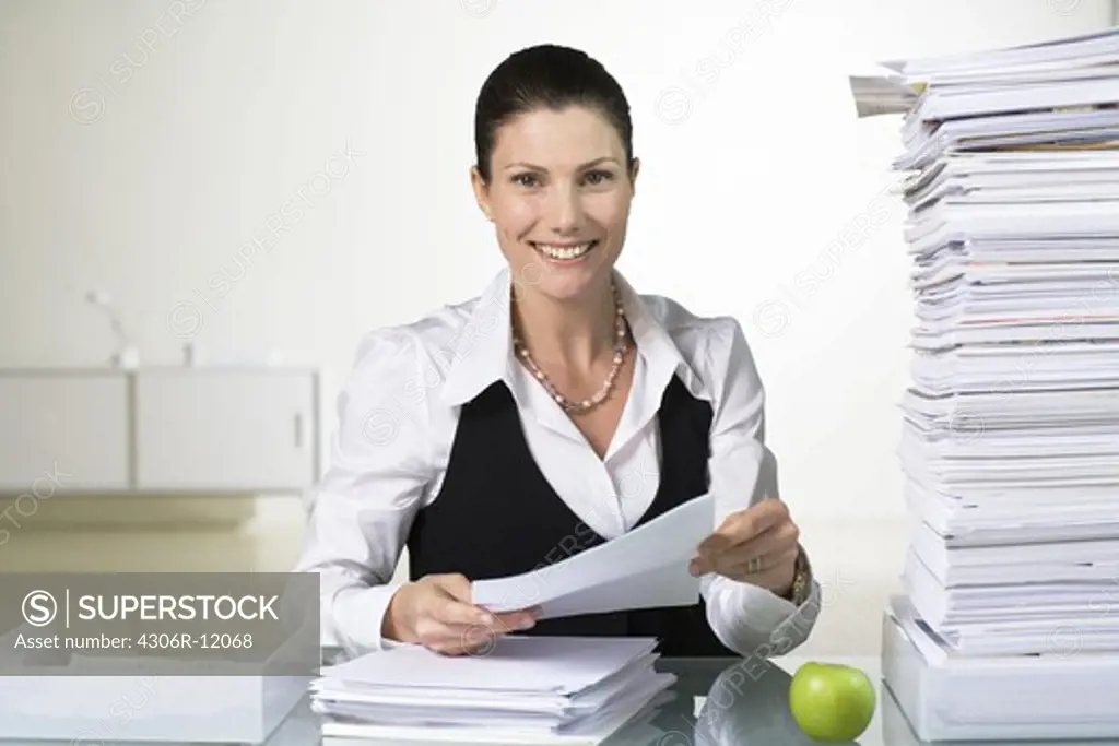 A smiling woman doing paperwork.