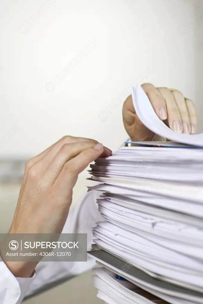 Two hands browsing through a pile of paper in an office.