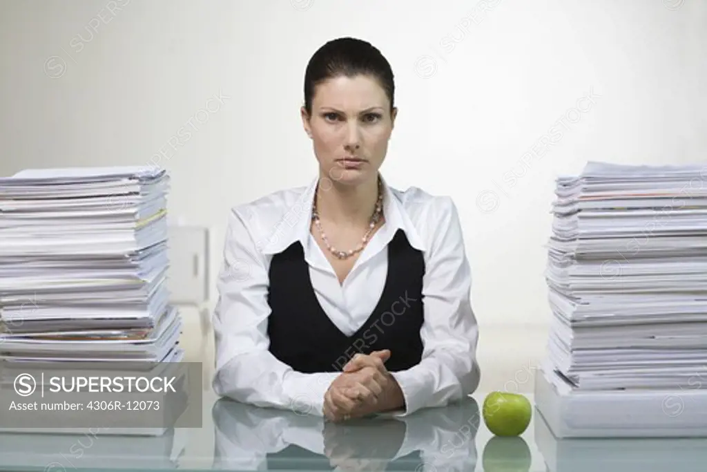 A woman in an office next to a pile of paper.