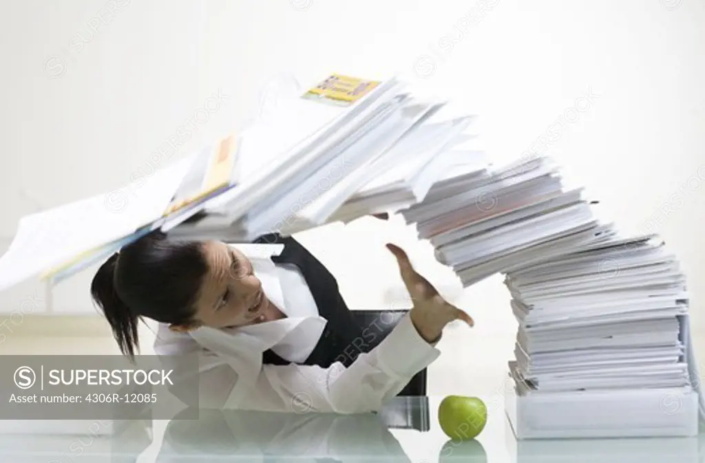 A woman in an office with a large pile of paper.