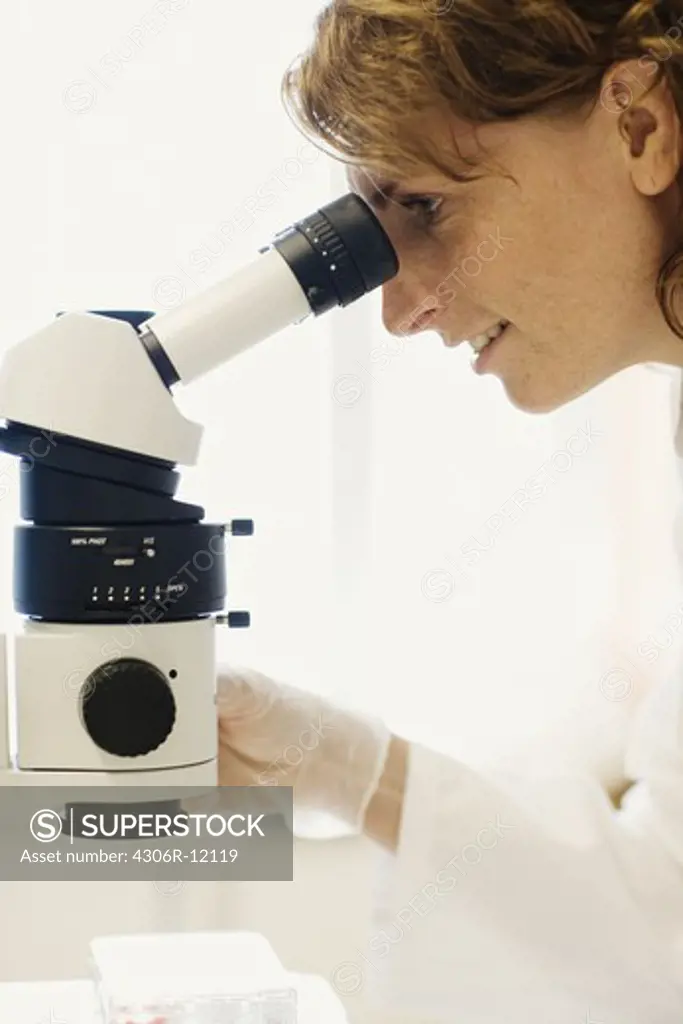 Female researcher with a microscope in a laboratory.