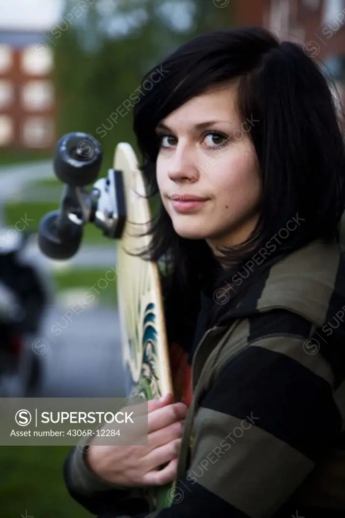 A girl holding a skateboard, Sweden.