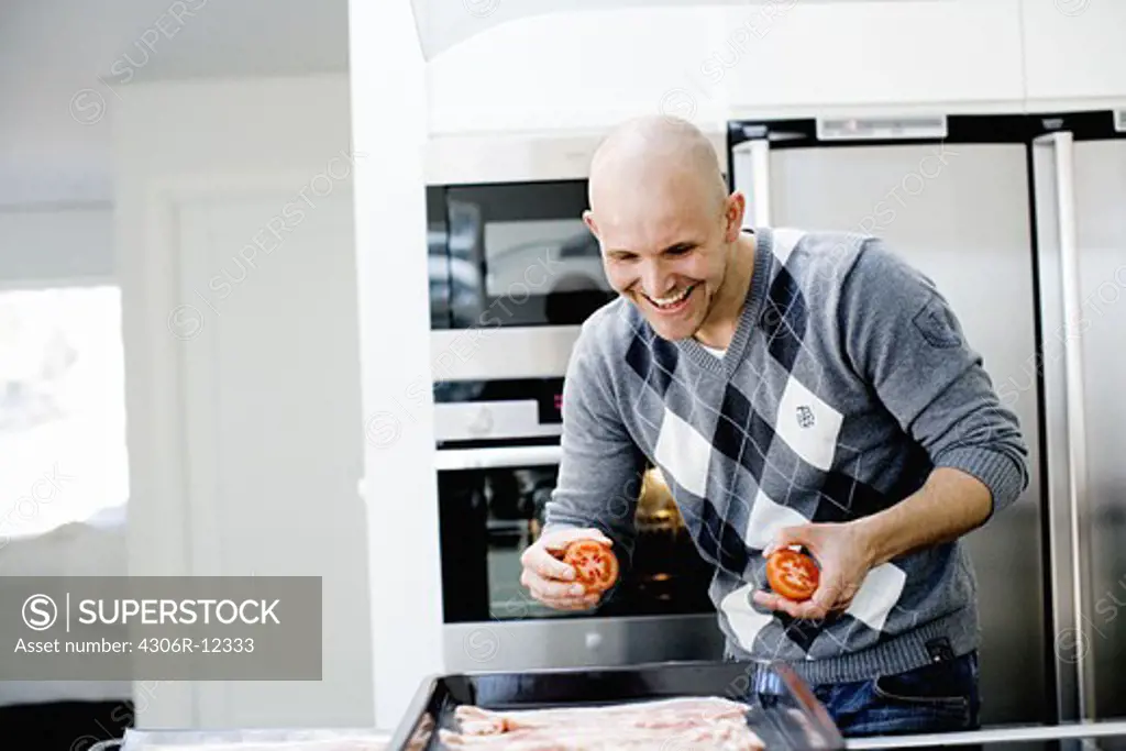 Smiling man coocking in the kitchen, Stockholm, Sweden.