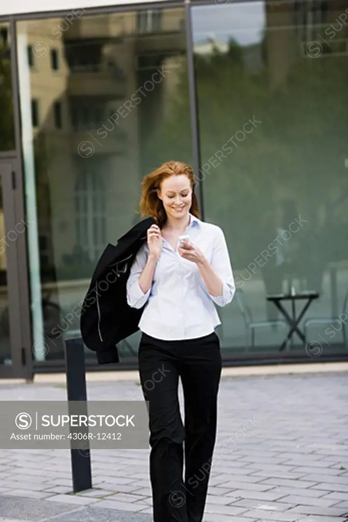 Woman walking outdoors talking in her cellphone, Stockholm, Sweden.
