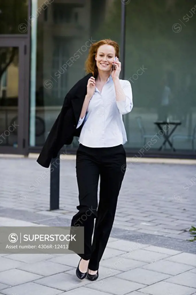 Woman walking outdoors talking in her cellphone, Stockholm, Sweden.