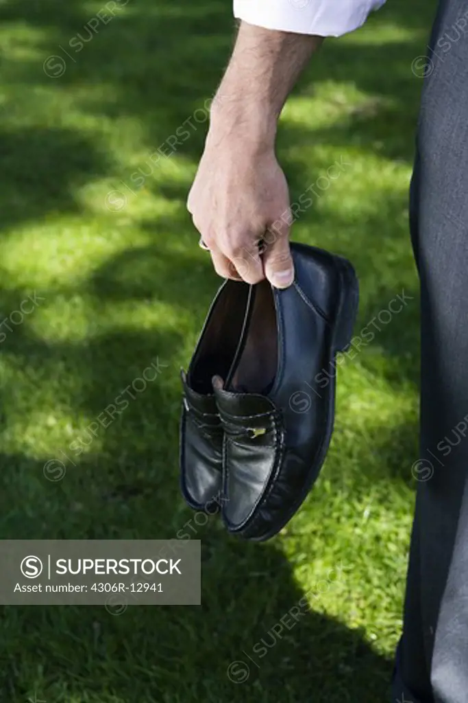 Businessman holding his shoes in his hand, Stockholm, Sweden.