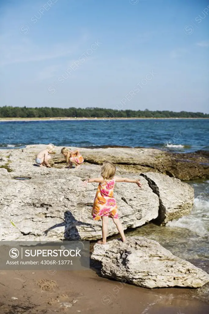 Children playing on cliffs by the ocean, Gotland, Sweden.
