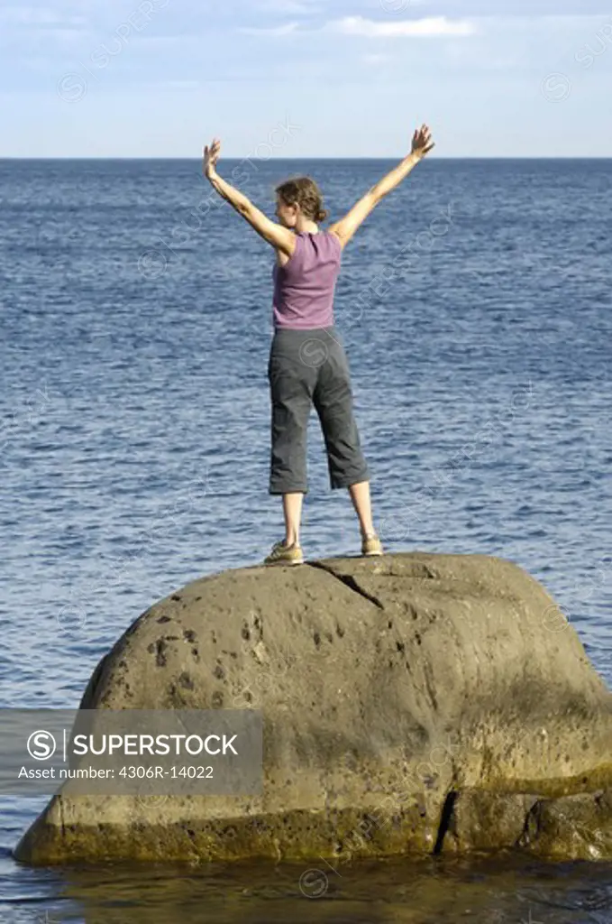 A woman standing on a cliff by the sea, Vaddo, Stockholm archipelago, Sweden.