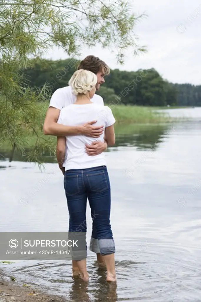 A couple standing at the water''s edge, Sweden.