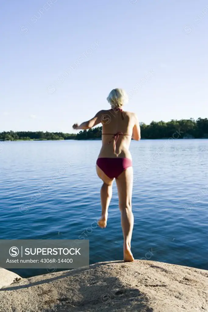 A woman jumping from a cliff in the archipelago of Stockholm, Sweden.