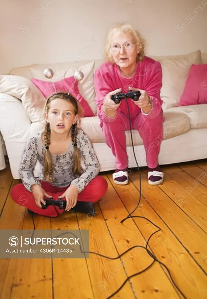 An elderly woman playing video game with her granddaughter, Sweden.