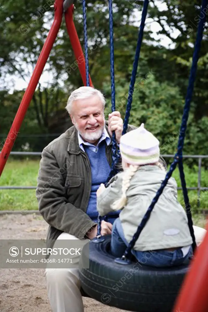 Grandfather and grandchild playing together on a playground, Sweden.