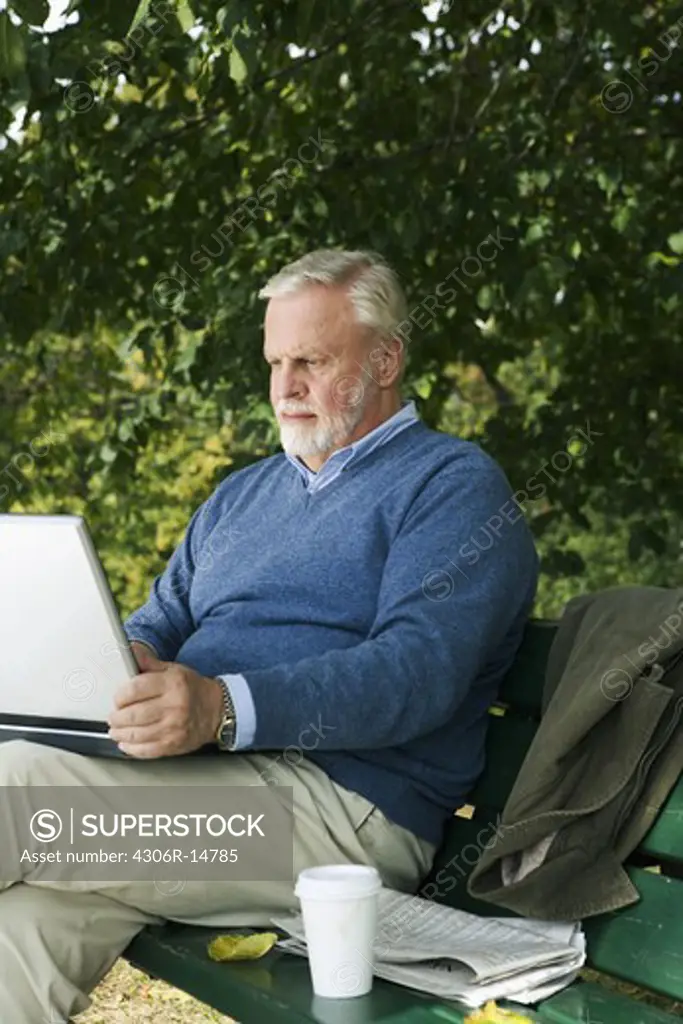 A man using a laptop in a park, Sweden.