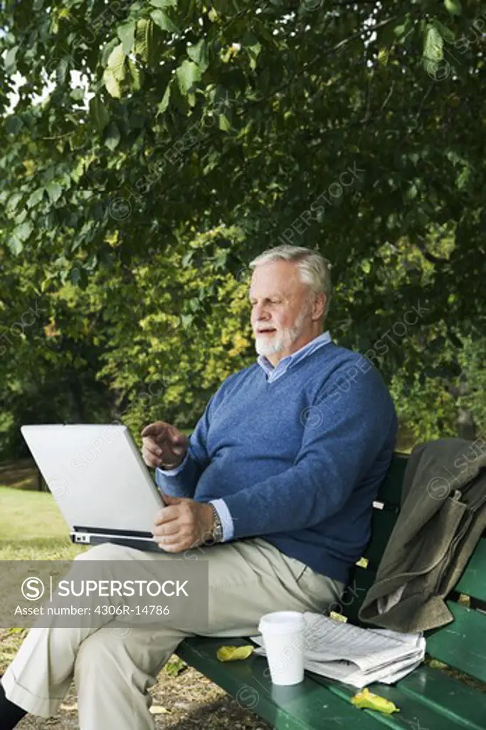 A man using a laptop in a park, Sweden.
