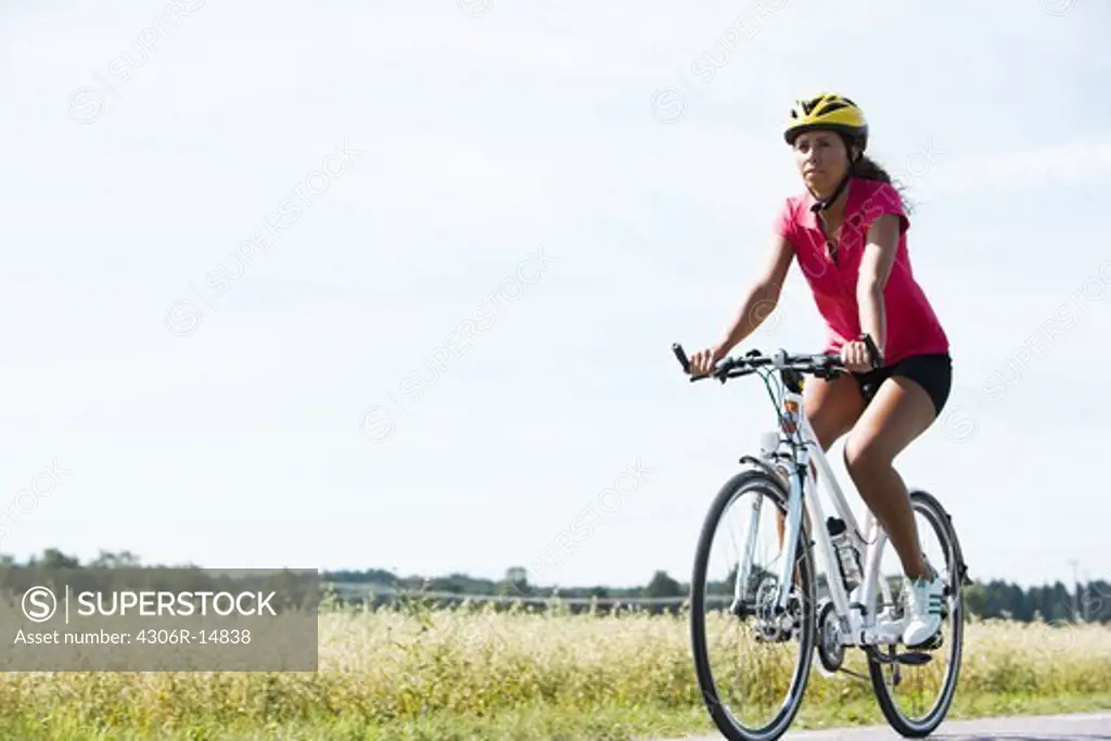 A woman riding a bike in the countryside, Sweden.
