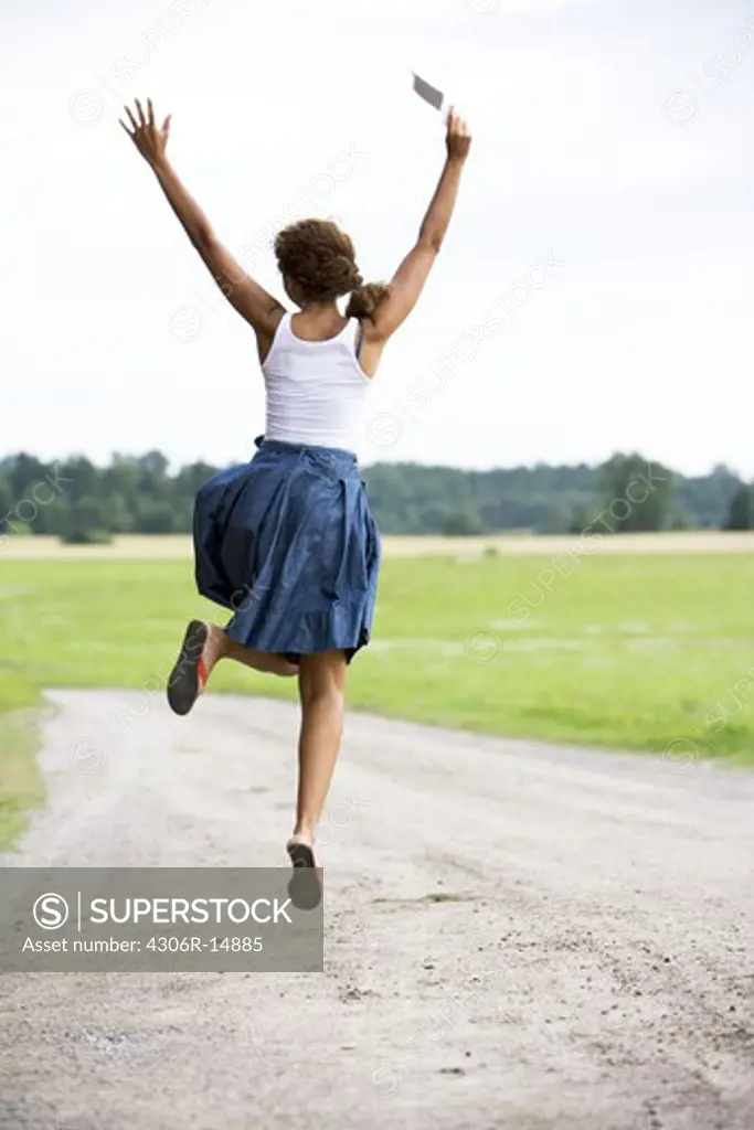 A girl jumping holding a letter in her hand, Sweden.