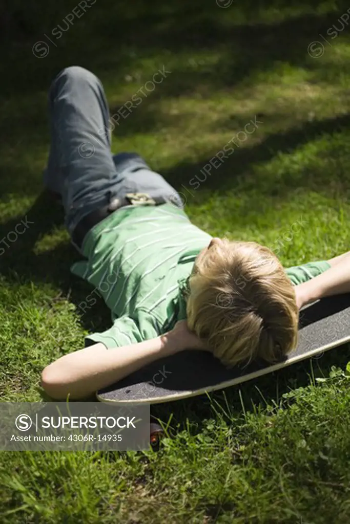 A boy resting on a skateboard, Sweden.