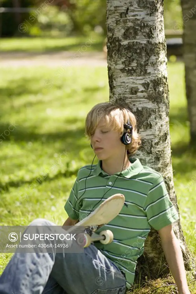 A teenager with a skateboard listening to music, Sweden.