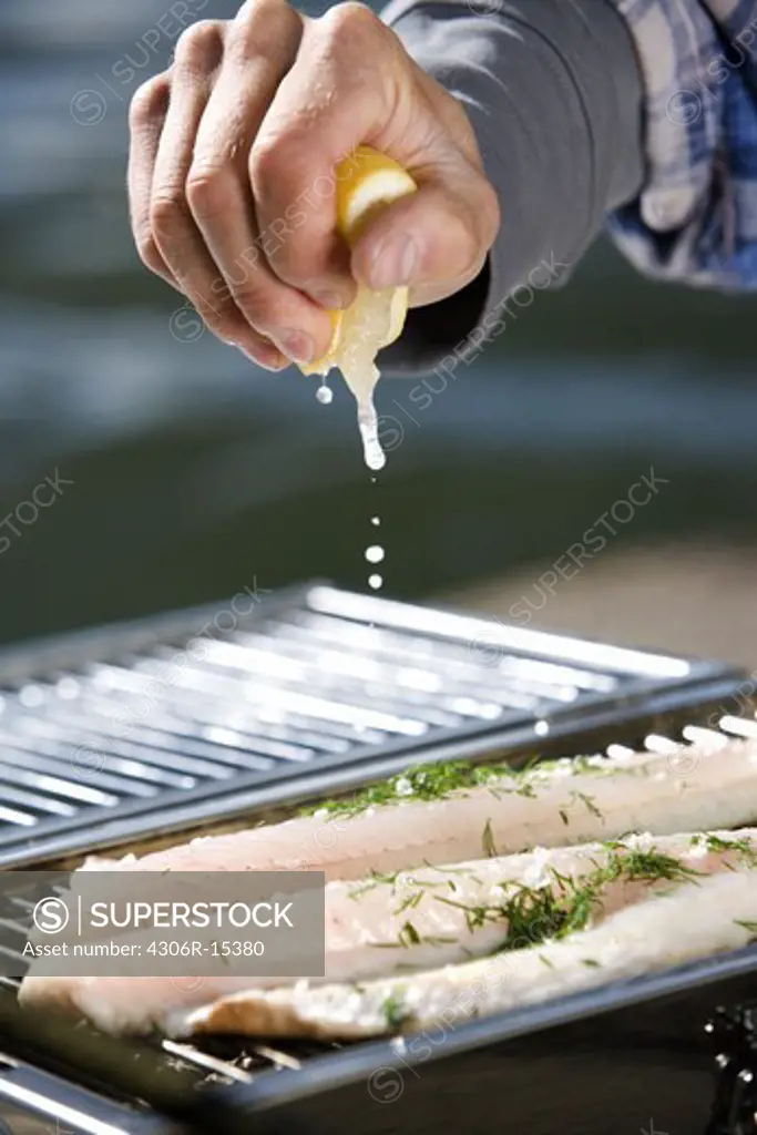 A man barbecuing fish by the water, Sweden.