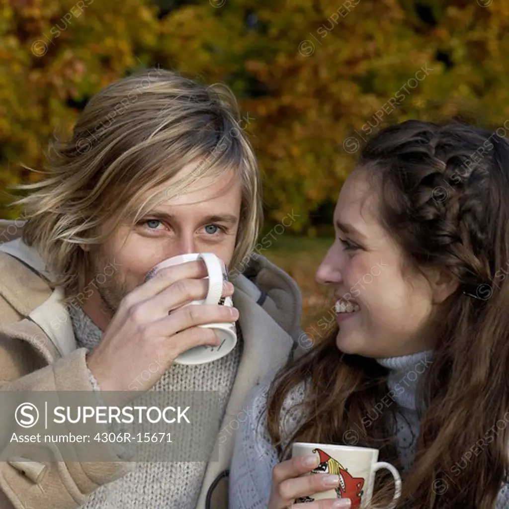 A couple having a cup of coffee in a park, Skane, Sweden.