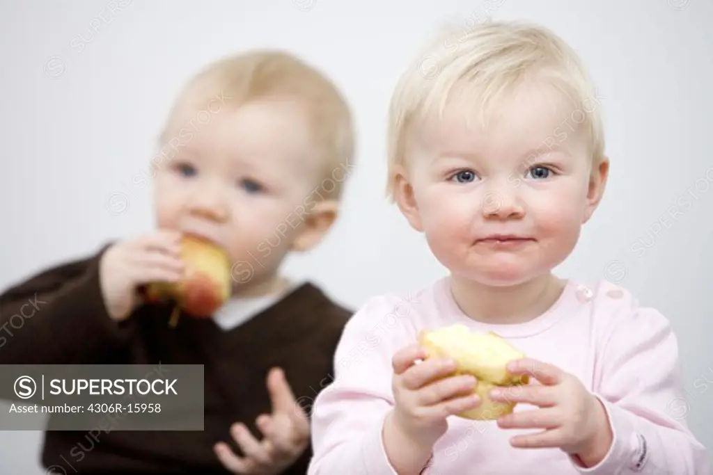 Two babies holding apples, Sweden.