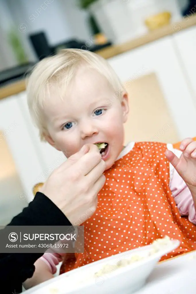 Blond baby girl eating, Sweden.