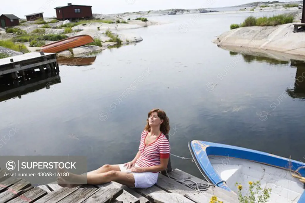 A woman sitting on a jetty in the archipelago of Stockholm, Sweden.